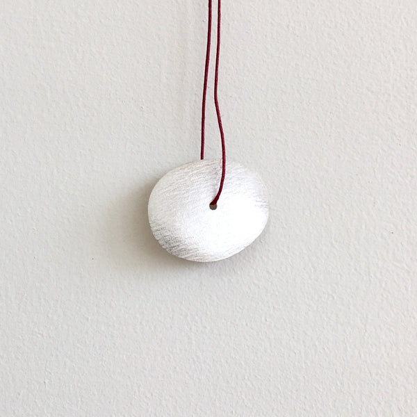 reverse side of textured oval on red thread with center hole - www.wyckoffsmith.com