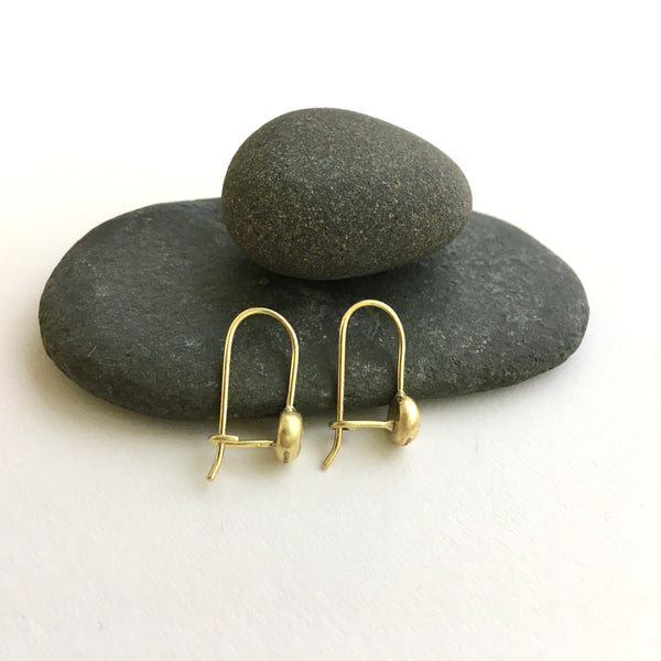 Side view of 18 ct recycled gold and diamond earrings resting against pebbles - www.wyckoffsmith.com