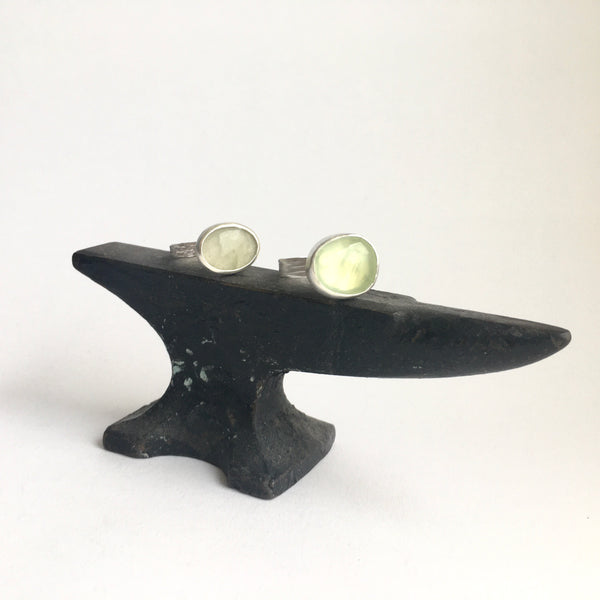 Two faceted prehnite stone rings (grey green on left, yellow green on right) on a mini jewellers anvil available on www.wyckoffsmith.com