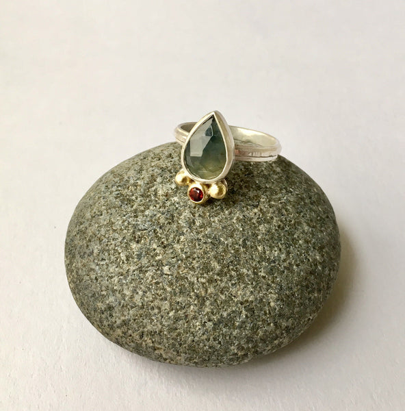 Blue green faceted sapphire with Mozambique garnet on a textured silver band by Michele Wyckoff Smith