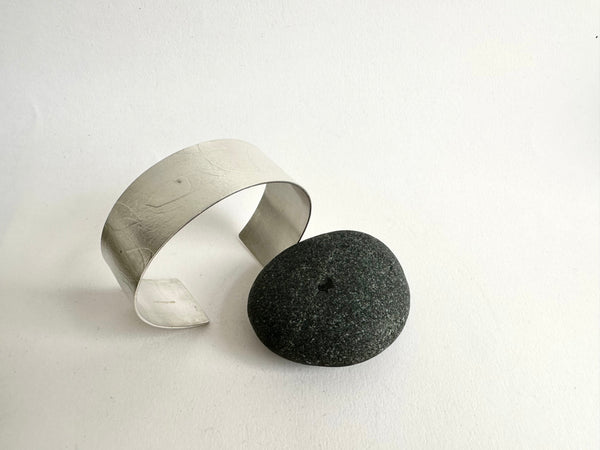 Side and top view of silver spindle leaf cuff  beside black pebble - www.wyckoffsmith.com