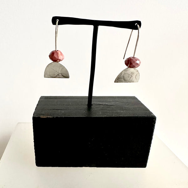 Pink faceted rhodonite bead on top of a half oval textured silver dangle earring. www.wyckoffsmith.com