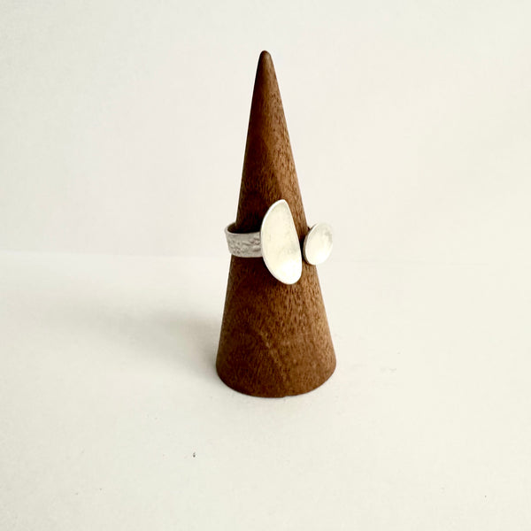 Side view of an open ring with contrasting shapes on a wooden cone. www.wyckoffsmith.com