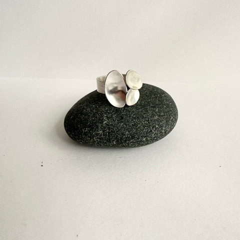 Triple oval open ring sitting on a dark pebble. www.wyckoffsmith.com