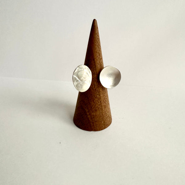 Front view of textured oval and concave circle shapes of an open ring sitting on a wooden ring holder. www.wyckoffsmith.com