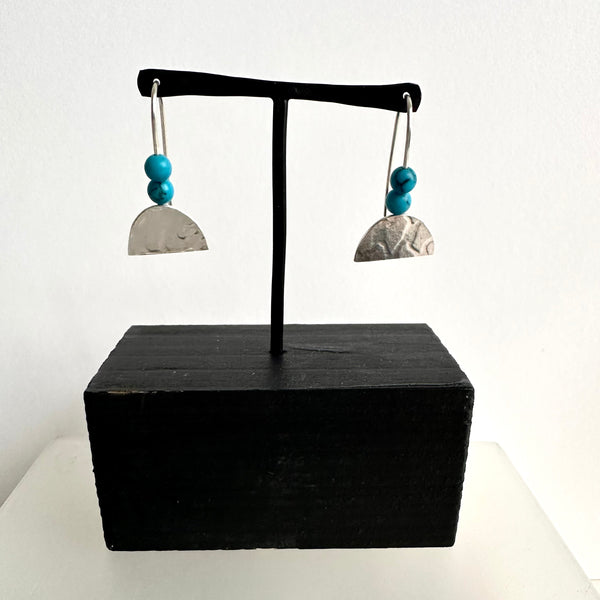 Double turquoise round bead with half oval textured silver dangle. www.wyckoffsmith.com