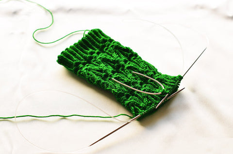 U shape silver cable needle on complicated green cable knit sock by Wyckoff Smith Jewellery www.wyckoffsmith.com