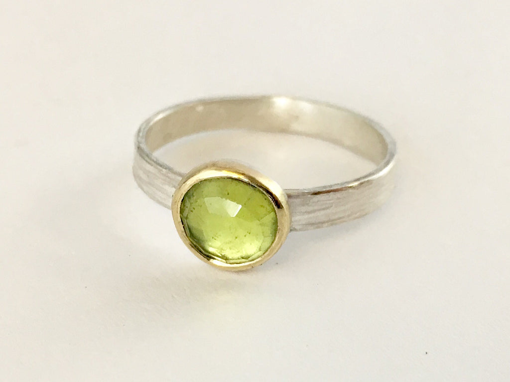 Light green faceted peridot ring set in 18 ct gold on a textured silver band by Michele Wyckoff Smith (UK)