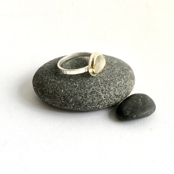Side view of ring on pebble - 18 ct gold set around pale grey moonstone - www.wyckoffsmith.com