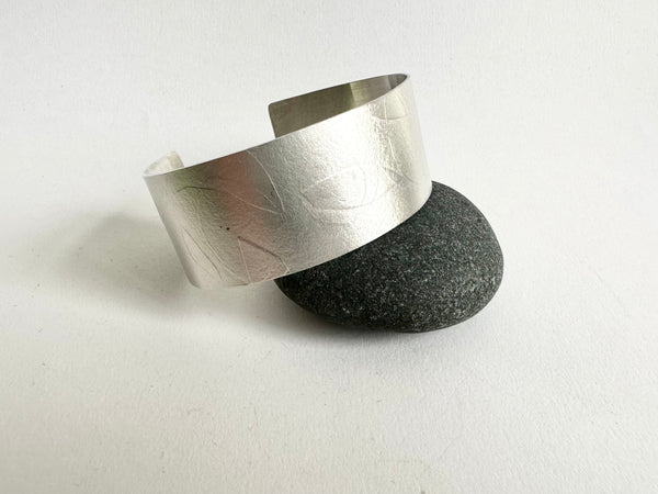 Spindle leaf silver cuff propped on black pebble - www.wyckoffsmith.com