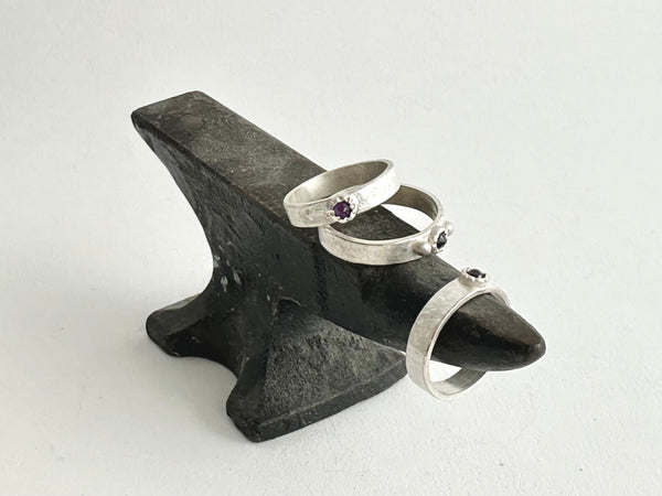 Assortment of Tudor set inverted stones (ruby, amethyst, sapphire) on a miniature anvil - www.wyckoffsmith.com