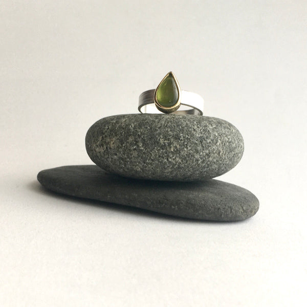 Front view of a green pear shaped indiocrase stacking ring on top of two pebbles. Silver and gold ring on www.wyckoffsmith.com