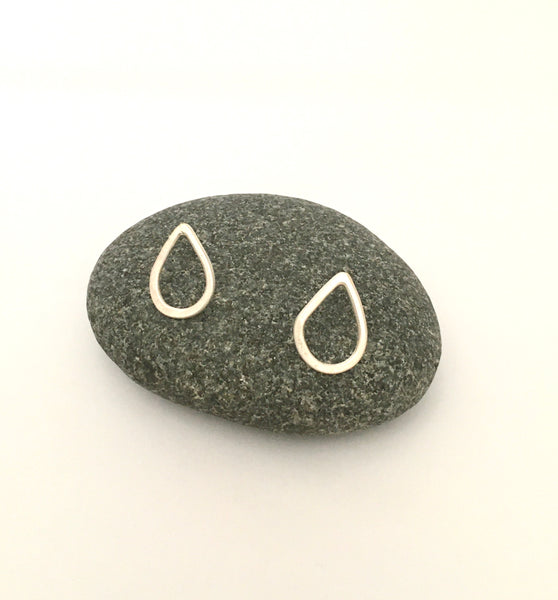 Pair or teardrop shaped silver hammered post earrings on gray pebble on www.wyckoffsmith.com