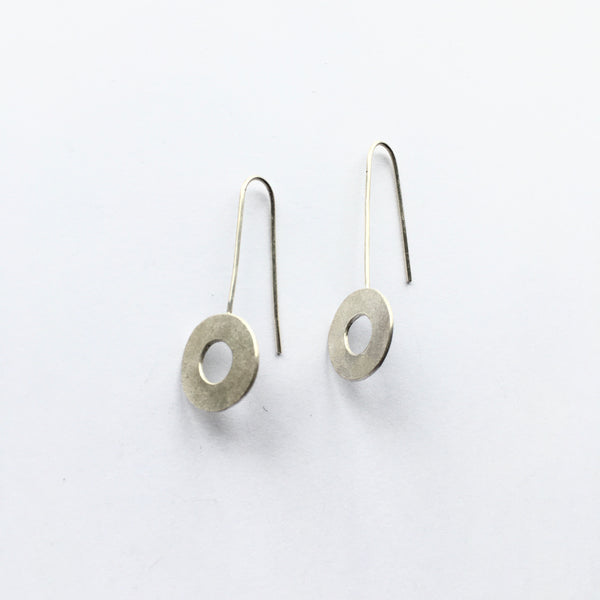 Side view of flat circle matte texture silver dangle earrings on www.wyckoffsmith.com