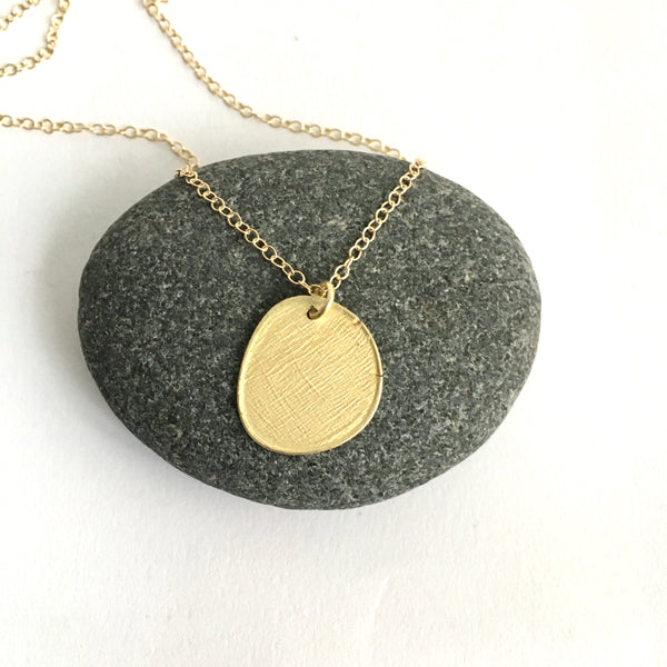 Textured 18 ct gold pendant with adjustable chain against pebble - www.wyckoffsmith.com