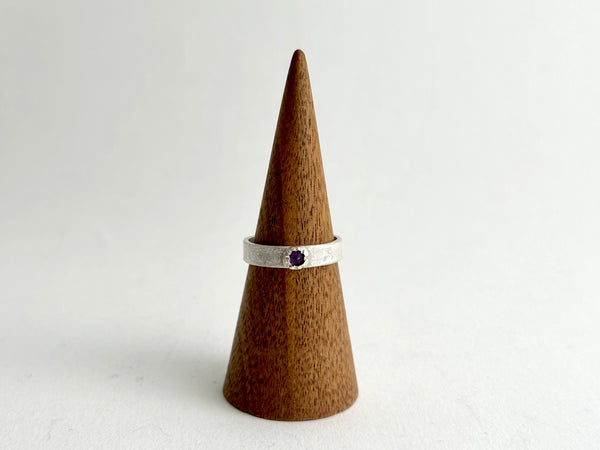 Tudor set inverted amethyst on a silver rough hammered band shown on wooden cone - www.wyckoffsmith.com