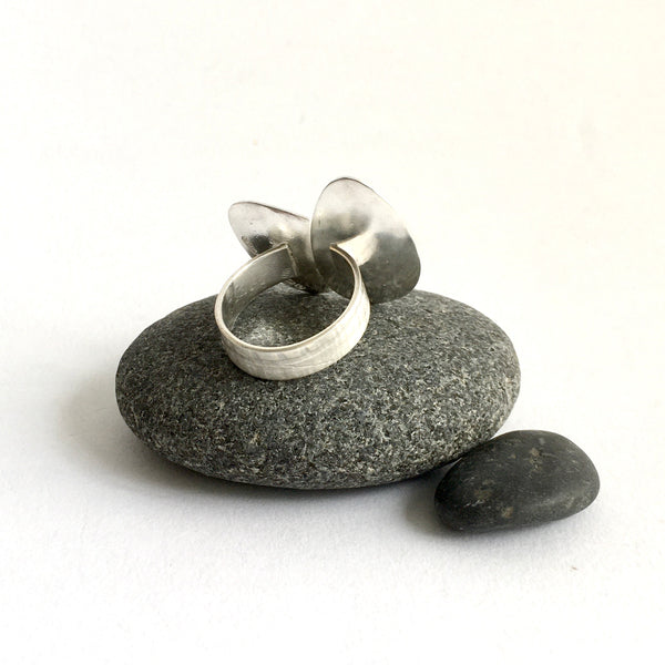 Back view of adjustable silver ring sitting on pebbles - www.wyckoffsmith.com