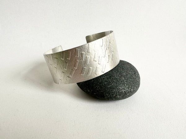 Side view of dash textured silver cuff with dark pebble - www.wyckoffsmith.com