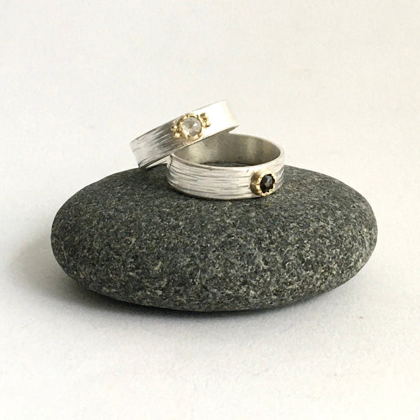 Two rose cut diamond rings sitting on top of a pebble - 18 ct gold hammer set bezel on a wide textured silver ring - www.wyckoffsmith.com