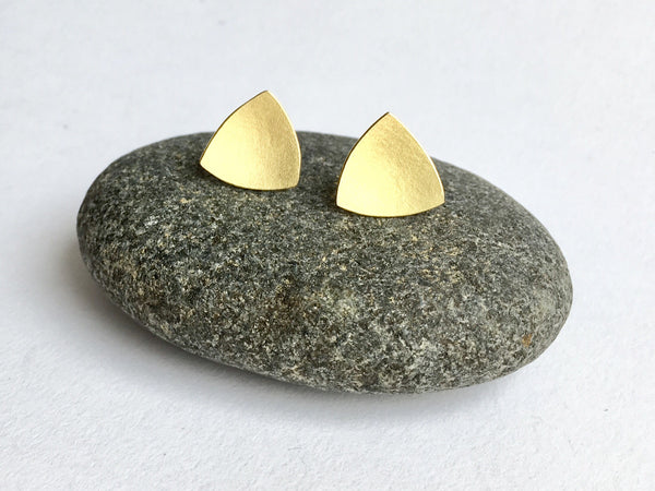 View of organic shaped 18 ct gold triangle stud earrings on pebbles by Michele Wyckoff Smith 