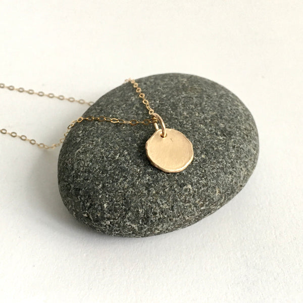 rough textured 9 ct gold pendant on dark pebble. Available on a 16" 18" adjustable gold chain. www.wyckoffsmith.com