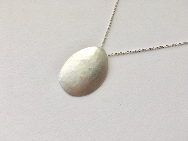 Convex egg shaped oval with light hammered texture and matte finish by Wyckoff Smith Jewellery.