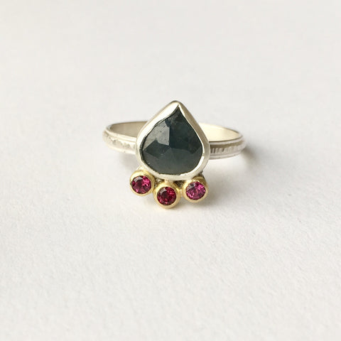 Blue green faceted sapphire ring with rhodolite garnets set in 18 ct gold. Wyckoff Smith Jewellery