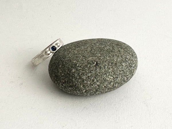 Tudor set sapphire ring next to a pebble - www.wyckoffsmith.com
