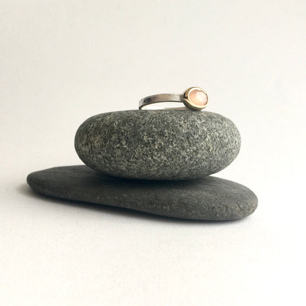 View of peach moonstone ring set in 18 ct gold on silver ring on top of two stones by Michele Wyckoff Smith on www.wyckoffsmith.com