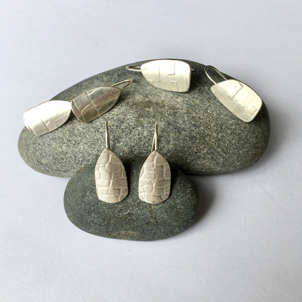 Three options of spinnaker earrings on pebble: option 1 - upper left; option 2 - upper right; and option 3 centre front on www.wyckoffsmith.com